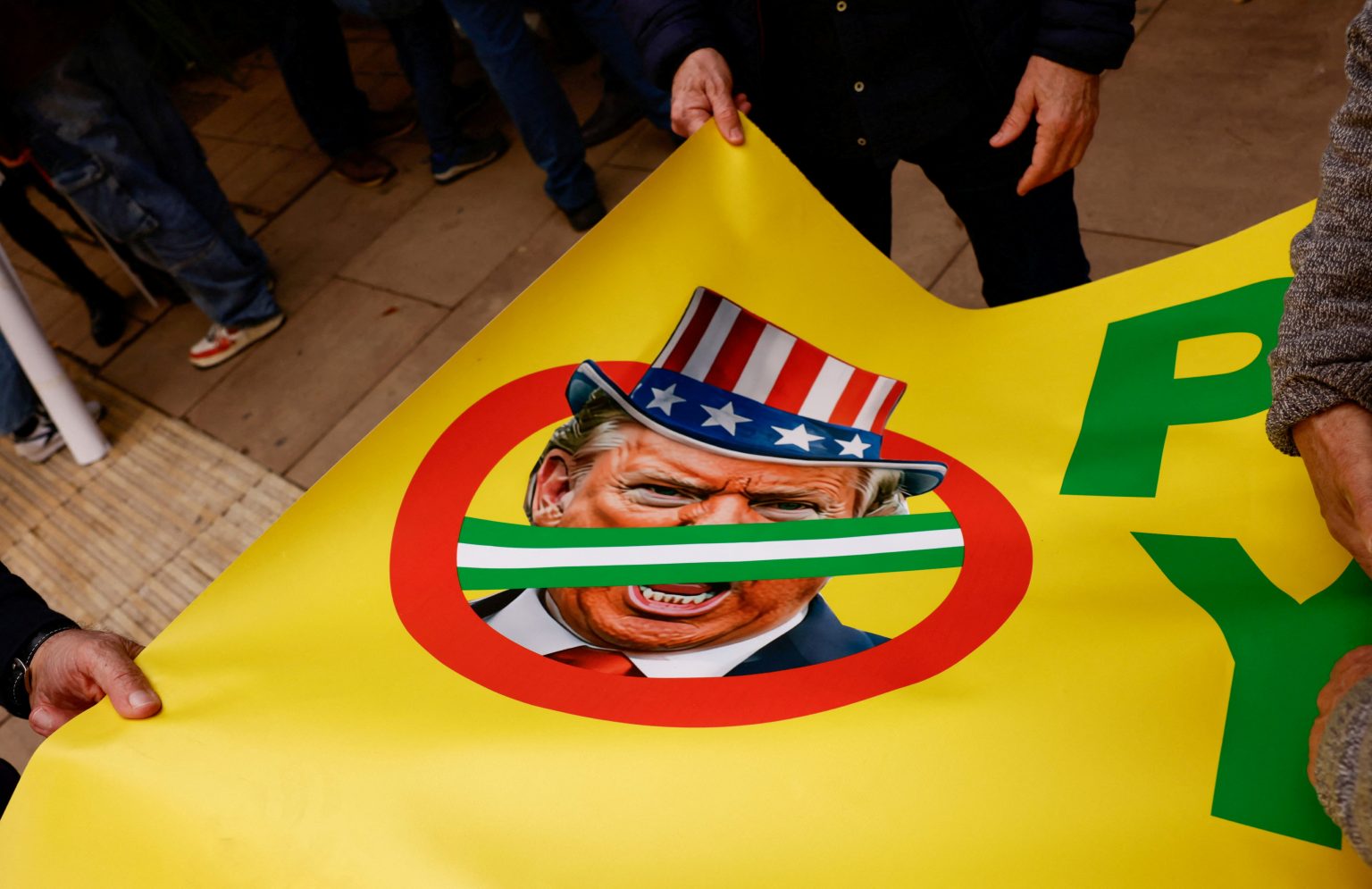 Ľudia držia transparent s podobizňou amerického prezidenta Donalda Trumpa počas protivojnového protestu, ktorý vyzýva na ukončenie nepriateľských akcií v rámci americko-izraelského konfliktu s Iránom, v španielskej Malage, 7. marca 2026. Foto: Jon Nazca/Reuters