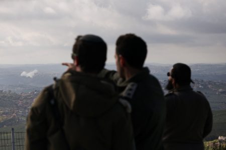 Israeli soldiers watch smoke rising after explosions in southern Lebanon.