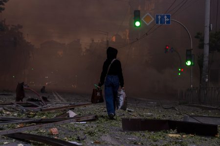 A woman walks on a debris-strewn street in Kyiv.