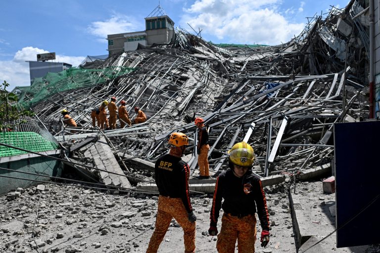 Rescue workers search for survivors in building debris.