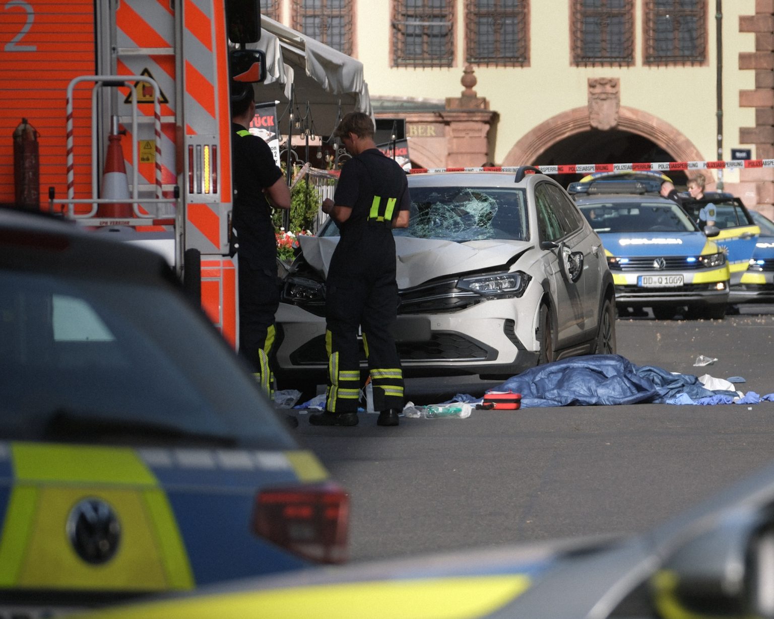 Rescue workers stand next to the damaged car after it was driven into pedestrians in Leipzig. Photo: Sebastian Willnow/picture alliance/Getty Images