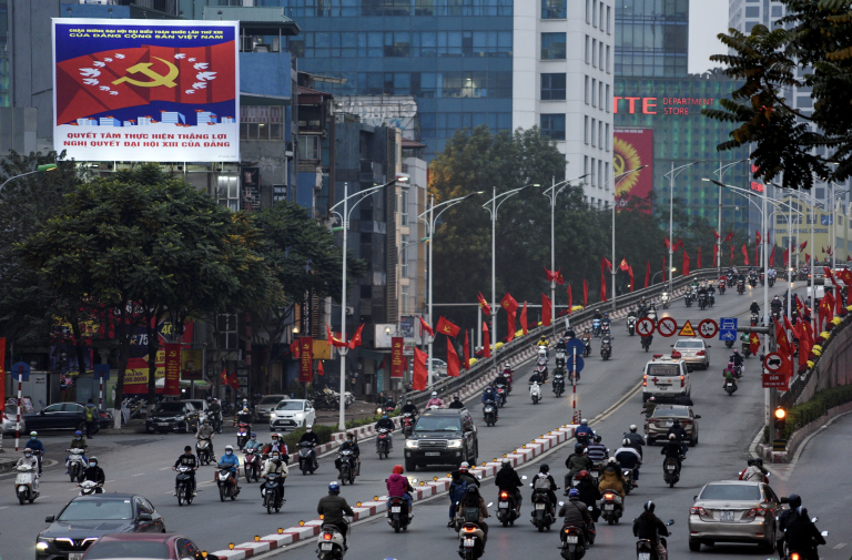 Cars and motorbikes pass banners for the Communist Party of Vietnam’s 13th National Congress in Hanoi. Photo: Thanh Hue/Reuters