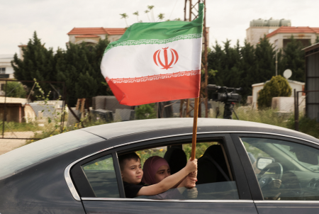 A child holds an Iranian flag from a car window. Photo: Aziz Taher/Reuters