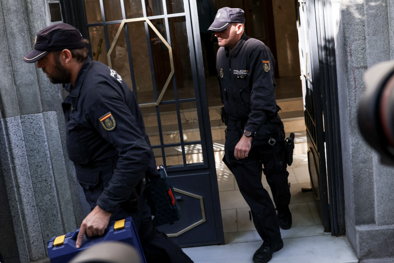 Police officers are carrying materials out of the office of José Luis Rodríguez Zapatero.