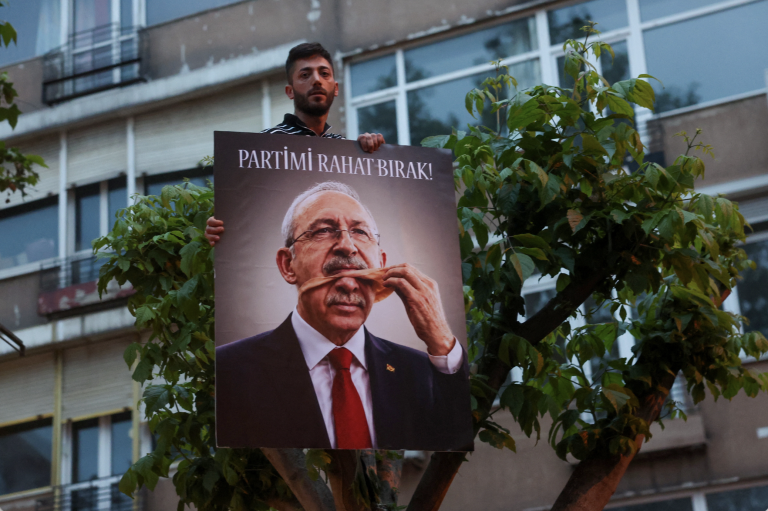 Podporovateľ Özgüra Özela, zosadeného predsedu hlavnej opozičnej Republikánskej ľudovej strany (CHP), drží fotografiu, na ktorej je znovuzvolený líder CHP Kemal Kilicdaroglu zobrazený, ako prezidentovi Tayyipovi Erdoganovi sníma masku so sloganom „Nechajte moju stranu na pokoji!“.