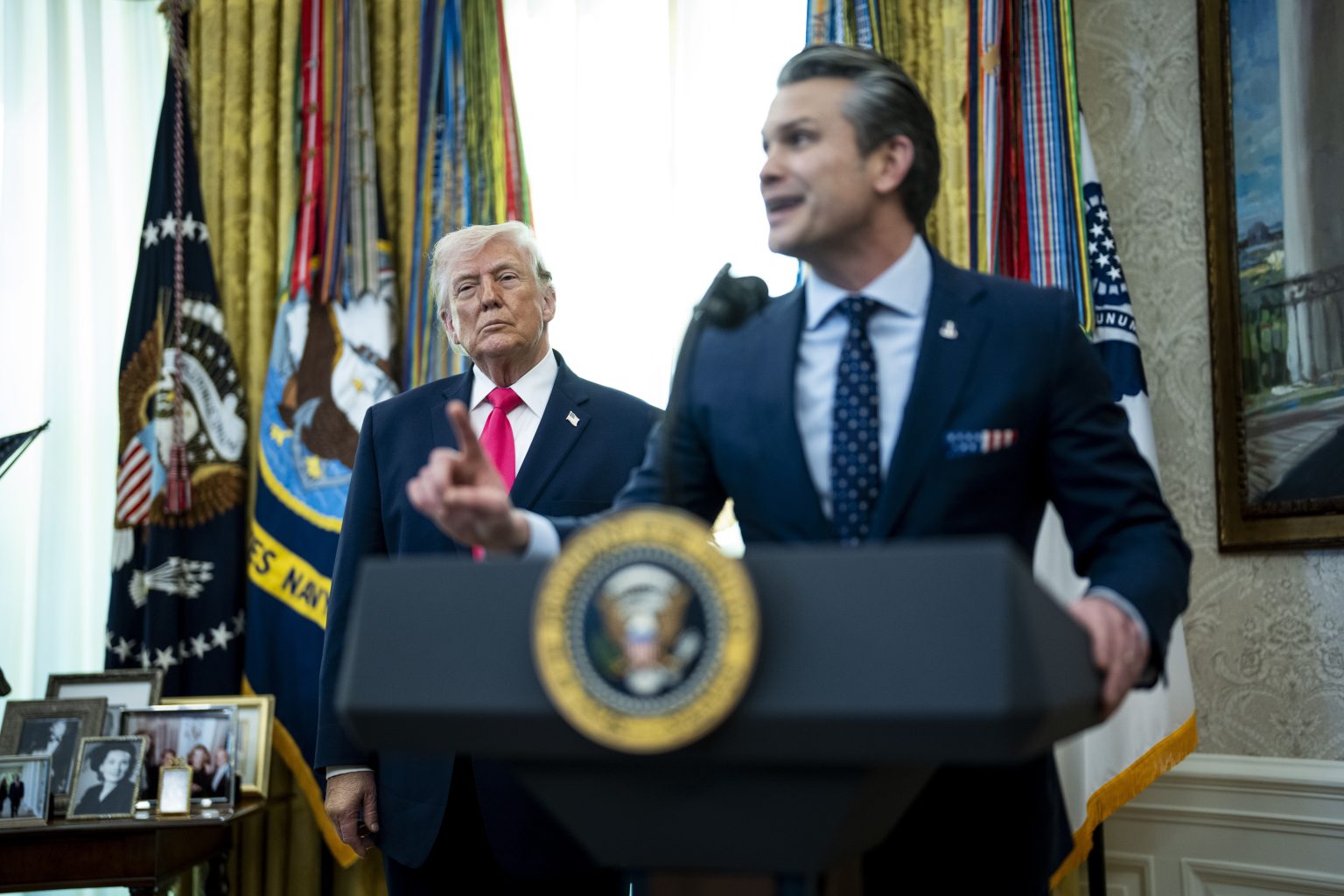 Pete Hegseth na tlačovej konferencii s Donaldom Trumpom v pozadí.