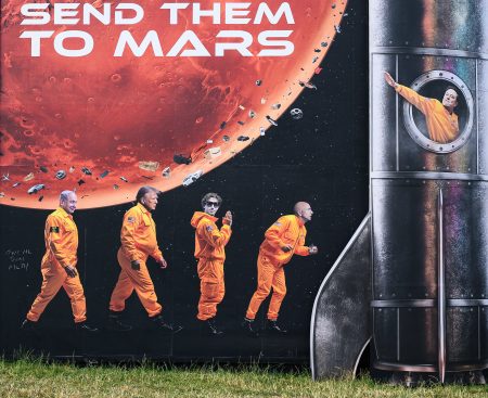 Účastník festivalu pred grafickým zobrazením miliardárov na Marse.