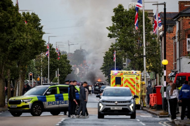 Polícia pri horiacej dodávke počas protestu v Belfaste.