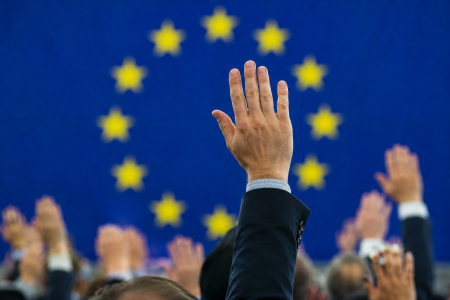 Raised hands and the European Union flag in the background.