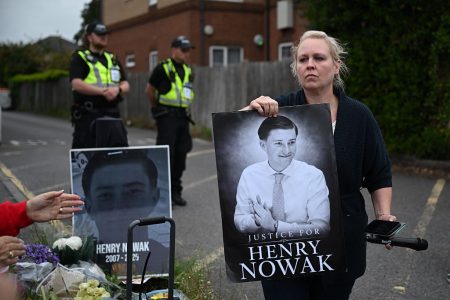 Protester holds a poster of Henry Nowak outside a police station.
