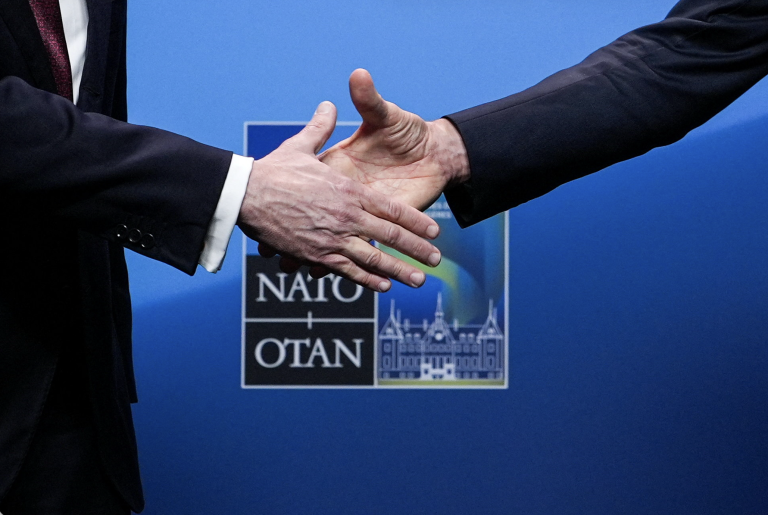 Podanie si rúk pred logom NATO.