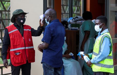 A Red Cross volunteer taking a person\'s temperature.