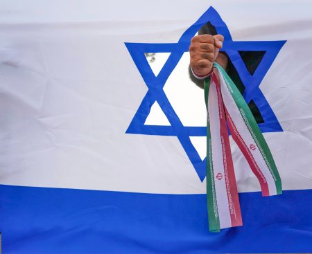 Iránsky protestujúci udiera do makety izraelskej vlajky.