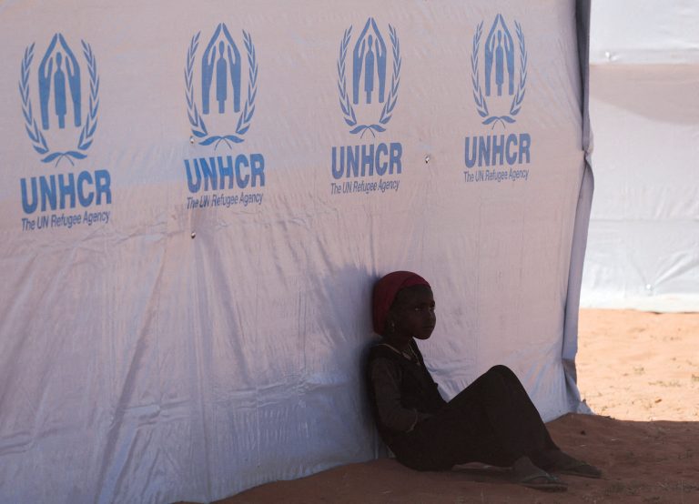 Utečenka odpočíva v tieni pri stane UNHCR.
