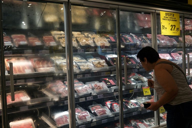 A woman looks at meat shelves in a supermarket.