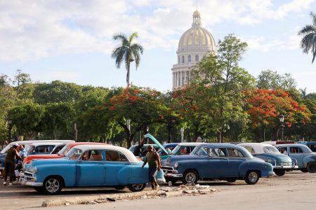 A man walks past vintage cars outside El Capitolio in Havana.