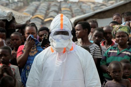 Health worker in PPE near displaced people.