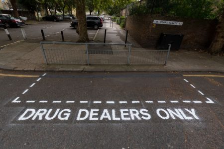Road markings reading “Drug Dealers Only” in Shoreditch.
