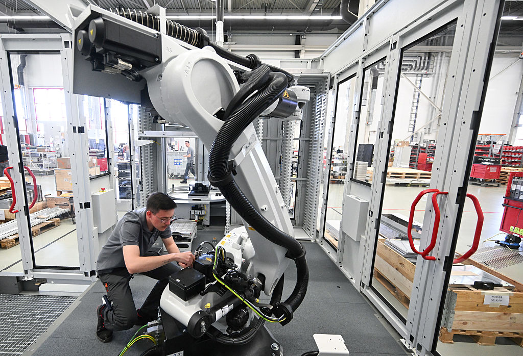A worker attends to a robotic arm at Hermle.