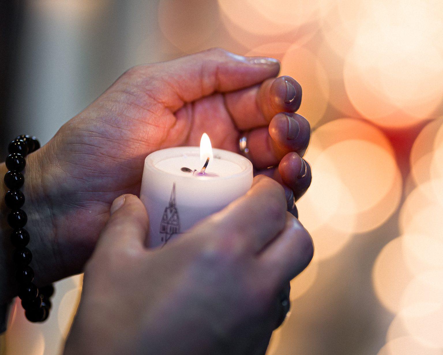 A woman holds a candle at a memorial service.