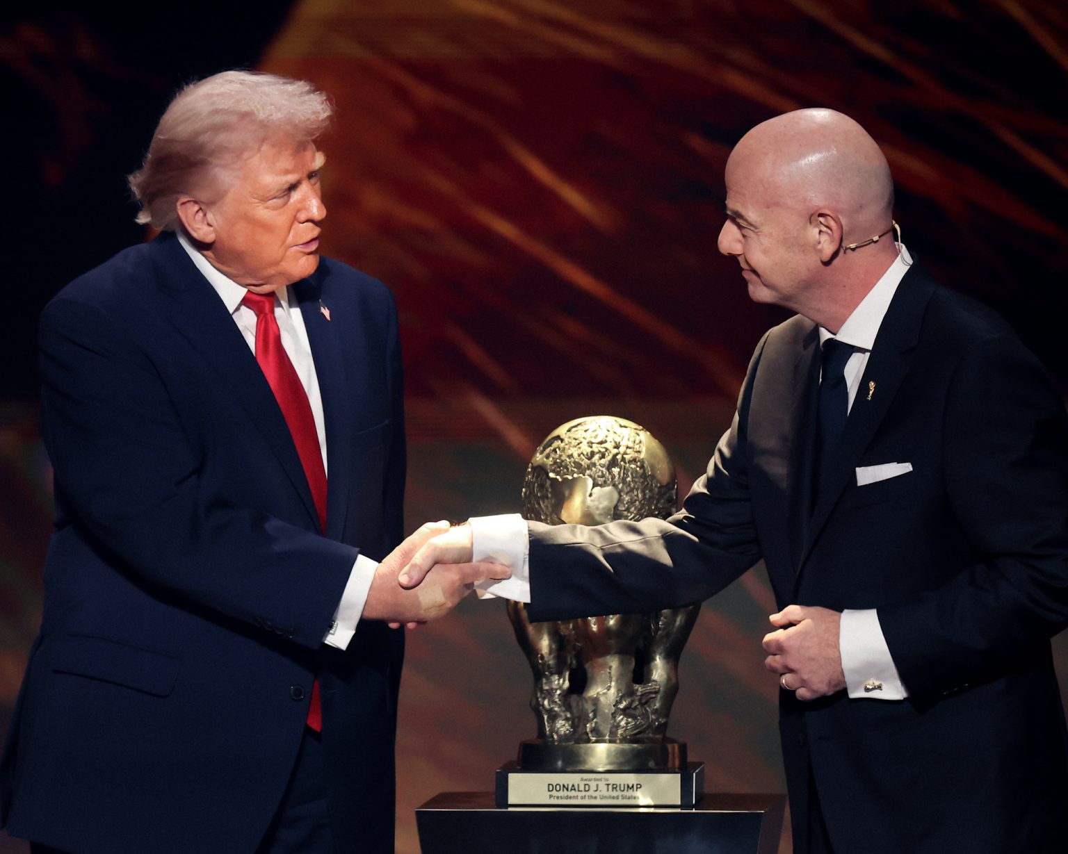 Gianni Infantino shakes hands with Donald Trump.