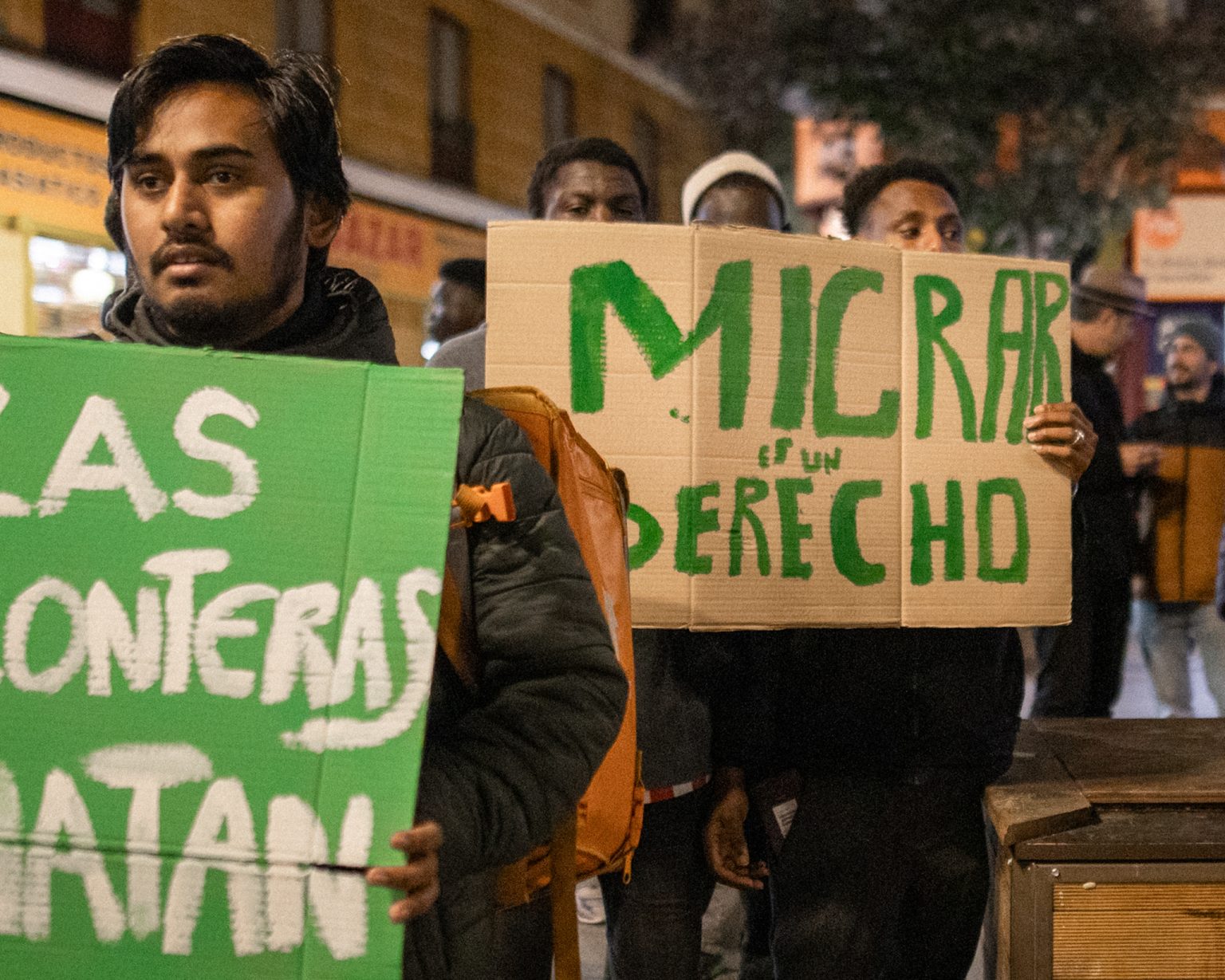 A migrant from Africa holds a sign saying 'migration is a right'.