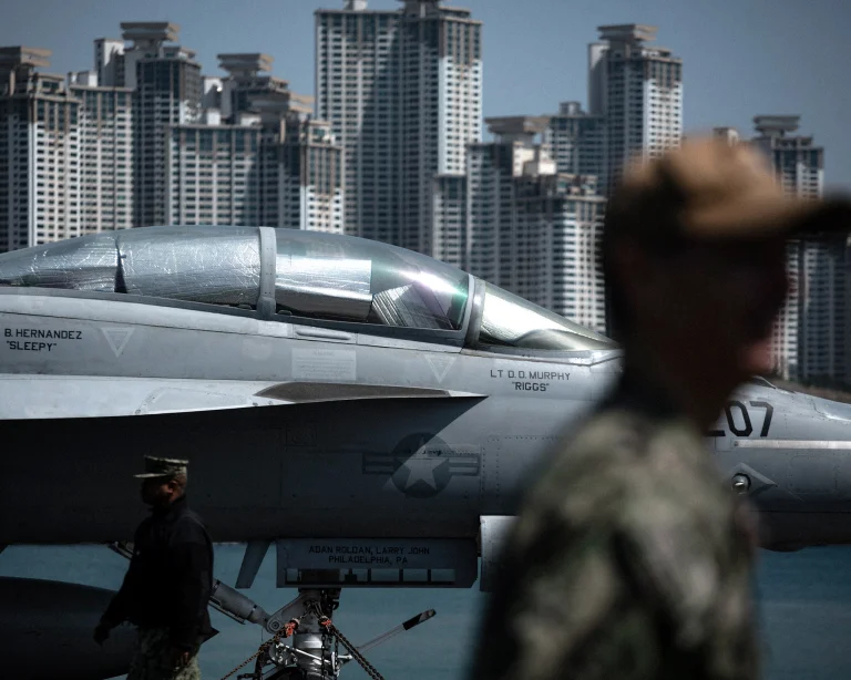 Crew members beside an F/A-18E on USS Nimitz.