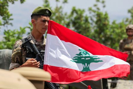 A soldier holds the flag of Lebanon.