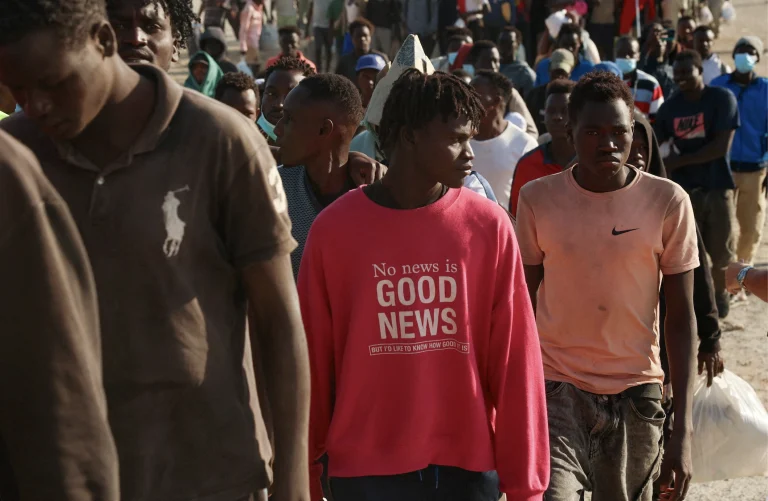 Migranti kráčajú z provizórneho tábora na pláži v Ceute.