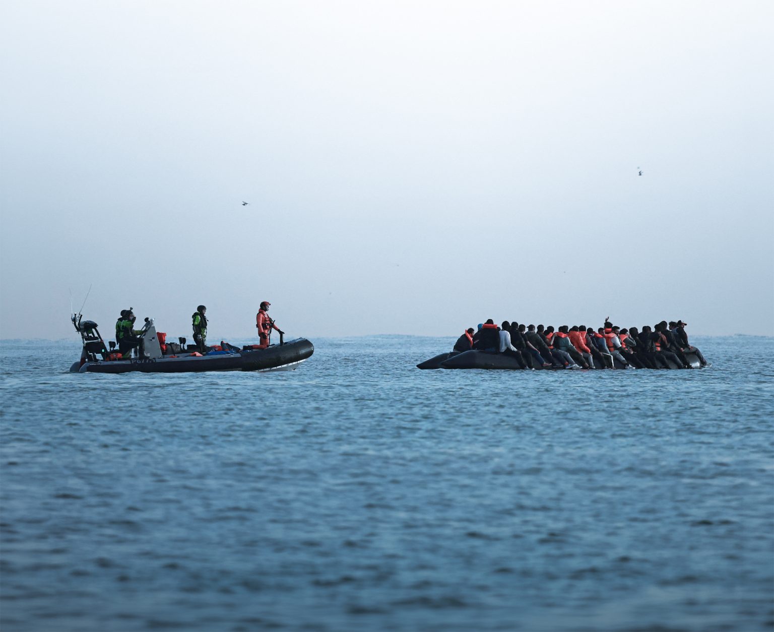 French police escort migrants across the Channel.