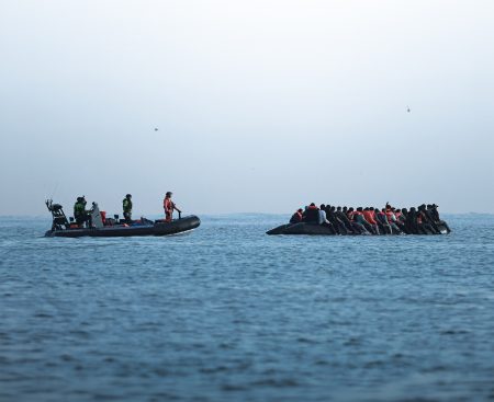 French police escort migrants across the Channel.