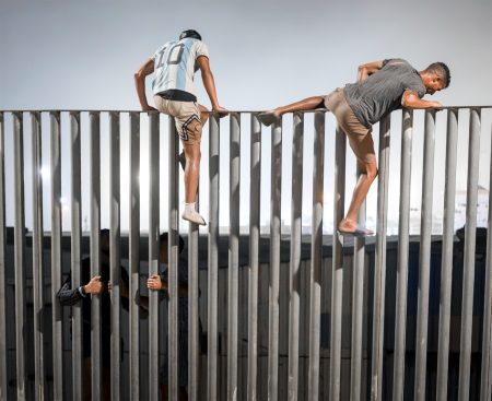 Migranti preliezajú plot na hranici Ceuty a Maroka.