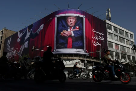 Ľudia jazdia okolo billboardu s Donaldom Trumpom v Teheráne.